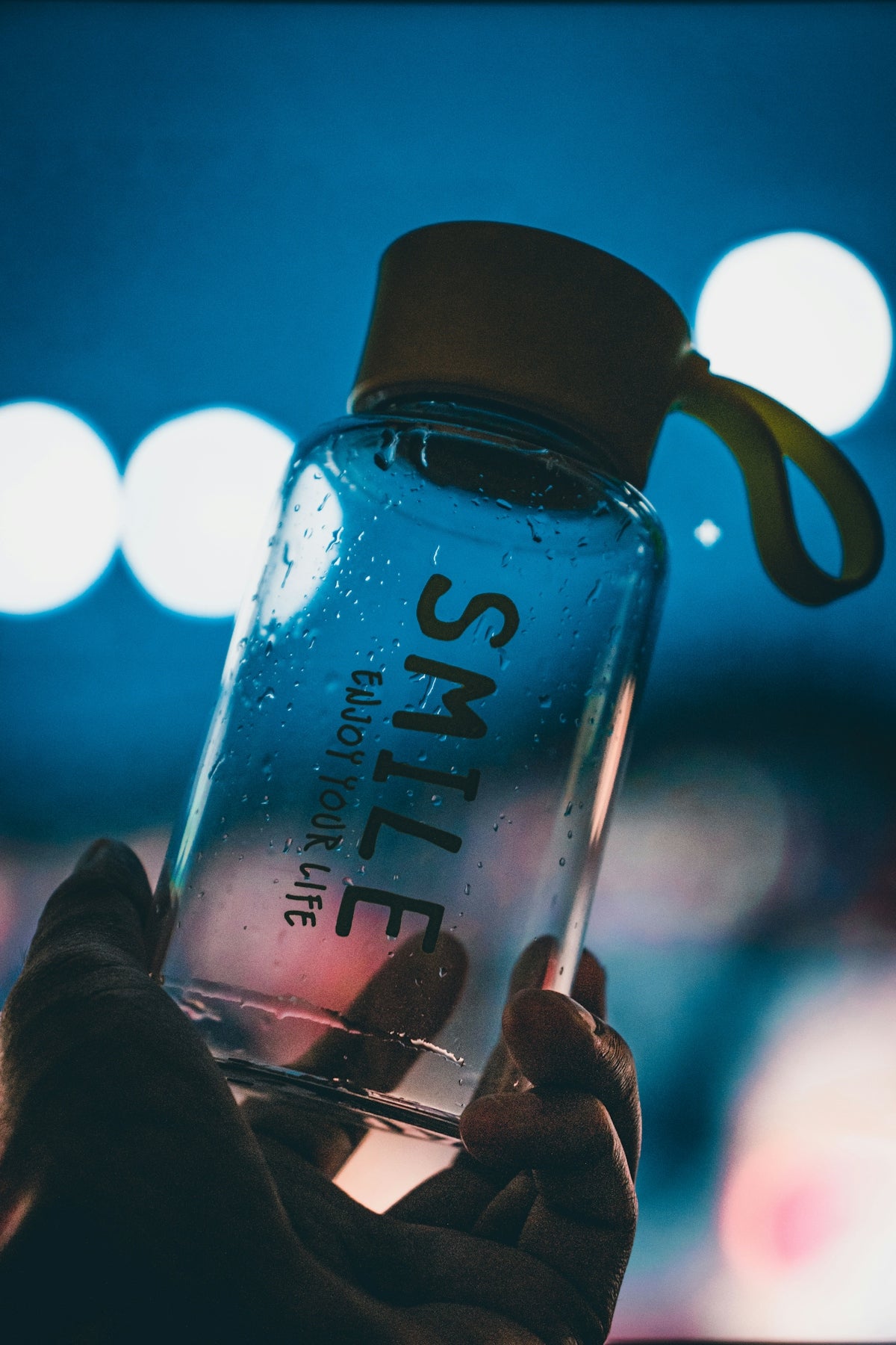 person holding clear glass bottle