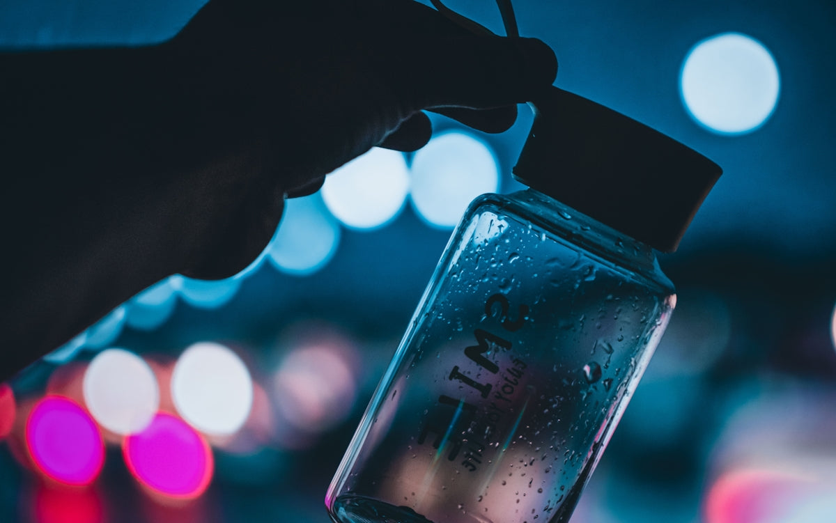 person holding clear glass bottle with water